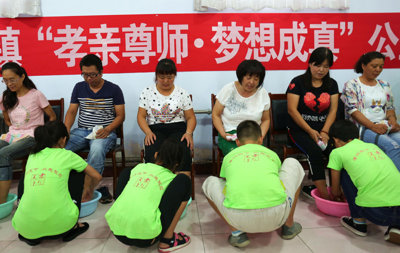 8月12日,河北省承德市营子区寿王坟镇南沟村小学生在夏令营活动中为父母洗脚。